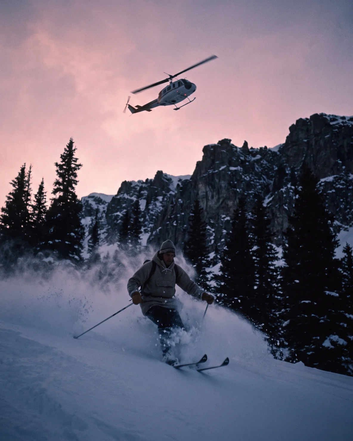 A skier carving deep powder at first light while the A-Star flies above the ridgeline behind them.