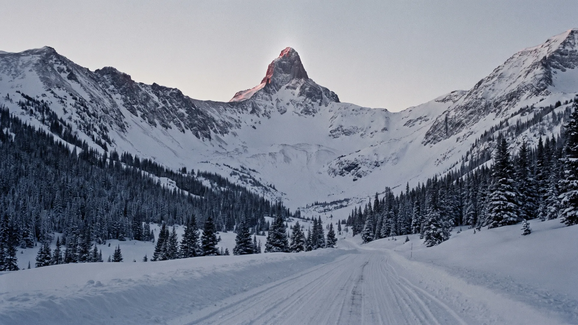 The Powderhorn basin at first light: the Horn's summit above open bowls, two descending ridgelines, fir glades on the lower slopes, and the creek road along the valley floor.